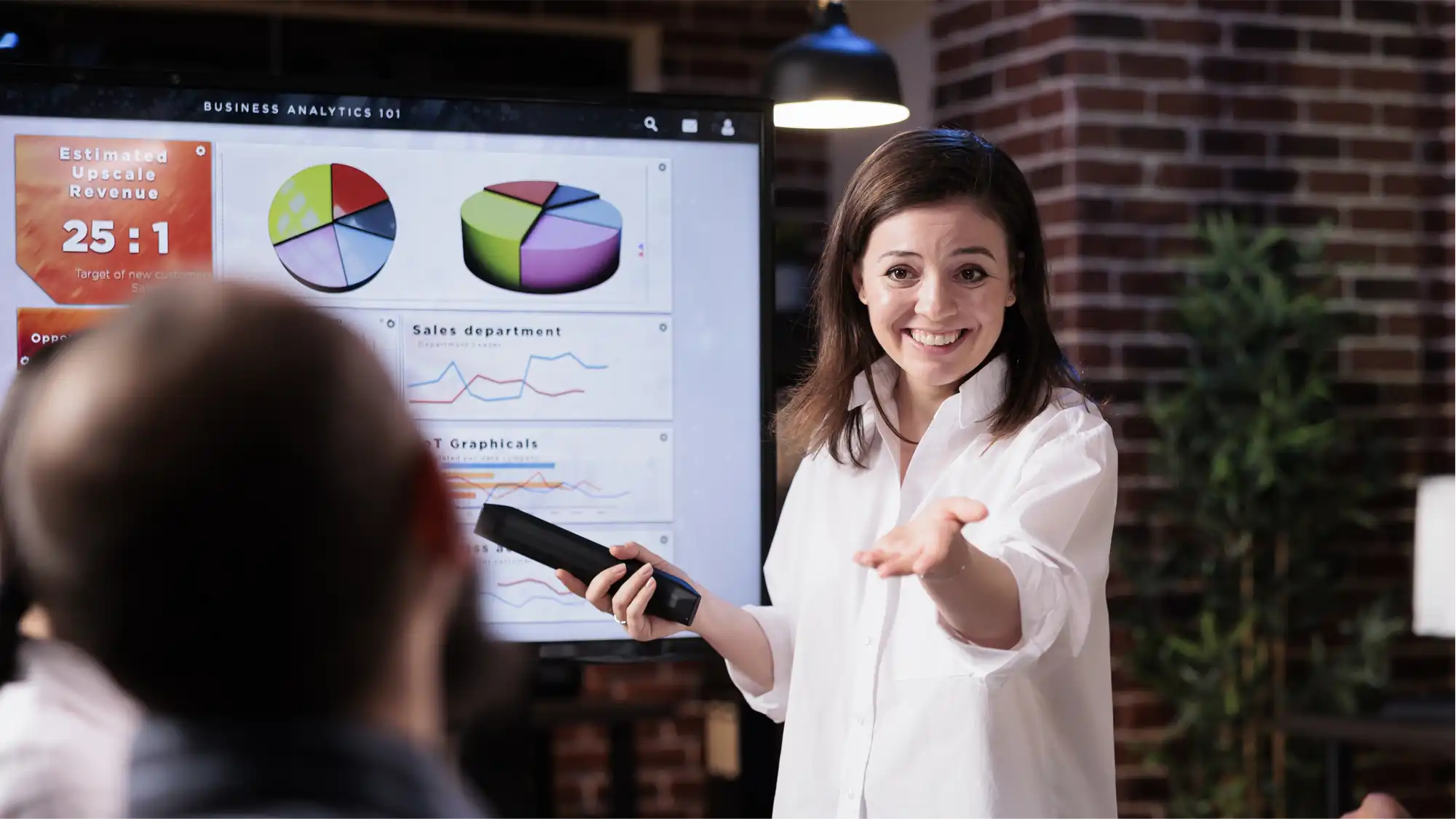 smiling businesswoman stands infront of screen showing charts about a high performing video marketing campaign