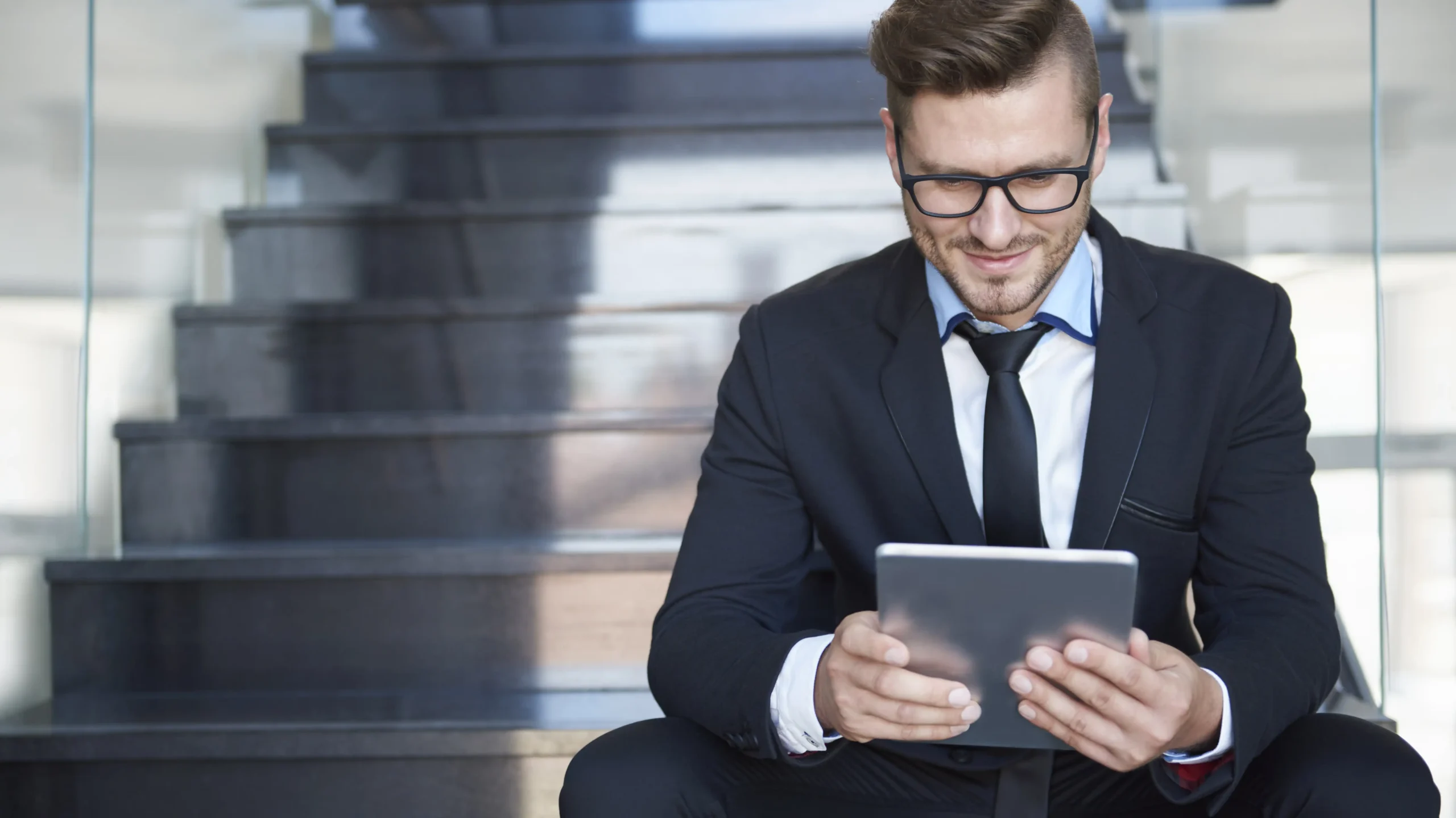 tech industry man sitting on steps looks at globalmeet virtual event on his tablet