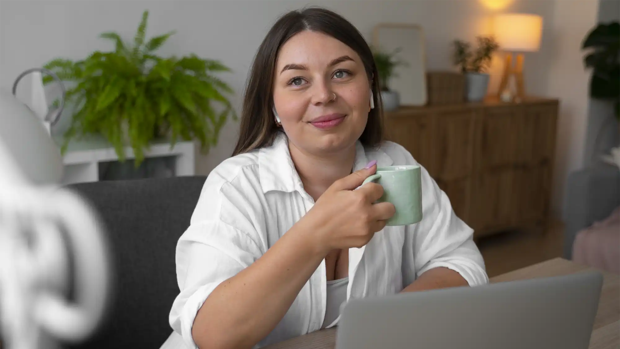 business woman sits at desk with cup in her hand considering globalmeet webcasts and globalmeet webinars