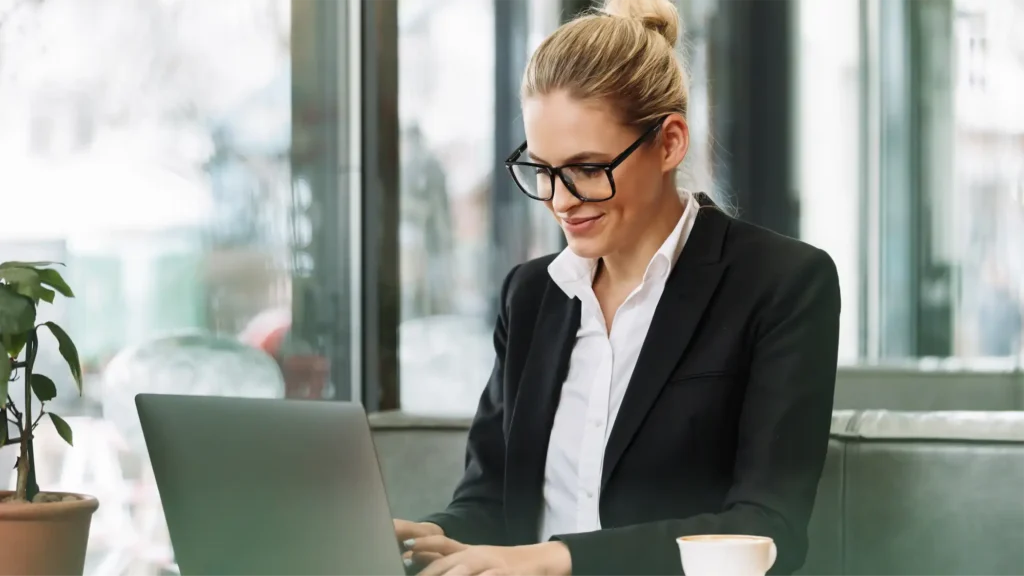 business woman wearing glasses sits in front of laptop considering globalmeet's virtual event best practices